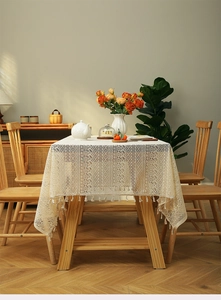 Detailed view of bohemian ivory lace tablecloth with hollow patterns and tassel edges