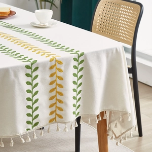 Fresh Nordic tablecloth with leaf embroidery and tassels on a wooden dining table