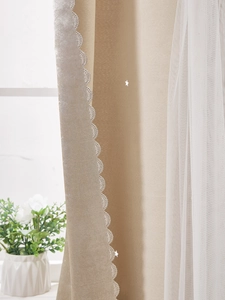 Dettaglio della tenda oscurante beige con stelle intagliate e bordo in pizzo elegante