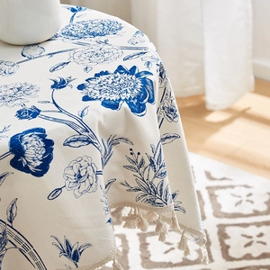 Detail of blue peony floral pattern on cream linen tablecloth with decorative fringes