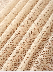 Close-up of bohemian beige lace tablecloth with vintage floral embroidery and fringe