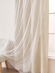 Dettaglio della tenda oscurante beige con strato di tulle bianco e motivi a stelle