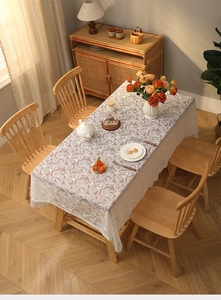 Detail of bohemian white lace tablecloth with embroidery and fringe on a wooden table