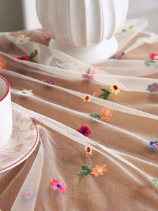 Close-up of colorful floral embroidery on semi-transparent lace mesh fabric material