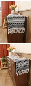 Close-up of black and white geometric woven table runner with decorative fringe tassels