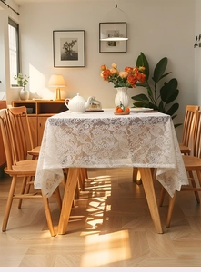Detailed view of white floral lace tablecloth with intricate crochet texture on a wooden table