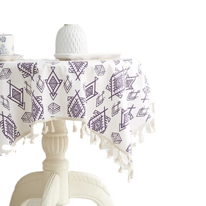 White tablecloth with purple geometric diamond print and cream tassel trim on round table