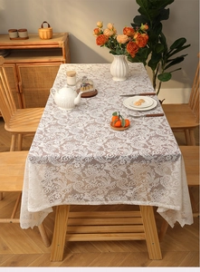 Close-up of white bohemian lace tablecloth featuring floral hollow patterns and tassel fringe