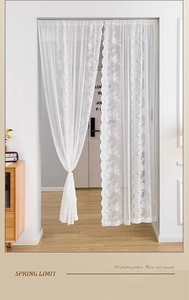 Détail de rideau de porte en dentelle blanche avec broderie florale et bords festonnés