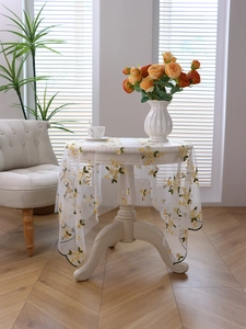 Detailed view of floral embroidery on white lace tablecloth with green wavy edges