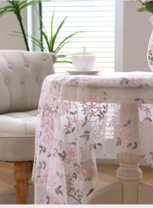 Close-up of pink and grey floral embroidery on white transparent lace mesh tablecloth