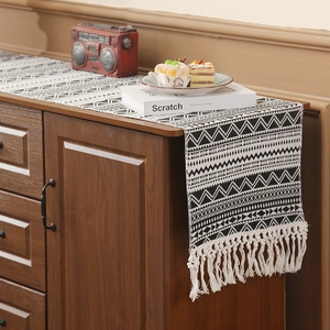 Woven geometric table runner with black and white patterns and elegant white tassels