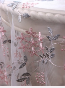 Close-up of elegant floral embroidery on translucent mesh lace tablecloth fabric