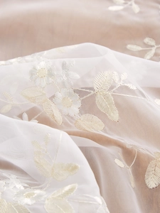 Close-up of elegant ivory tulle lace with delicate yellow daisy flower embroidery