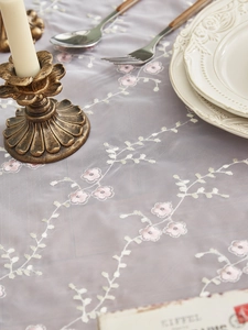 Detail der lavendelfarbenen Spitzentischdecke mit feiner Blumen- und Rebenstickerei