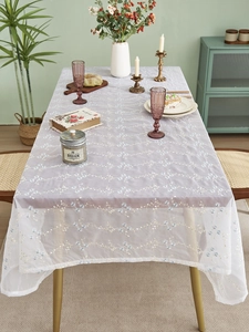 Detailaufnahme der fliederfarbenen Spitzentischdecke mit blauen und weißen Orchideen-Stickereien