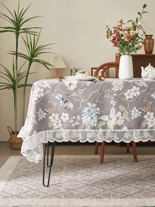 Detailed view of vintage floral tablecloth featuring white lace edges and flower patterns