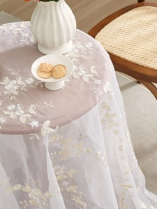 Close-up of beige lace tablecloth featuring floral embroidery and mesh texture detail