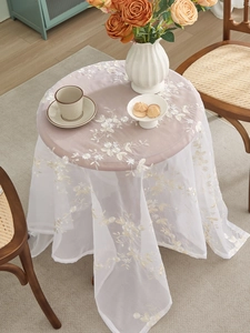 Close-up of elegant white floral embroidery details on delicate lace mesh tablecloth