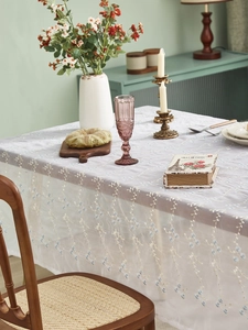Nahaufnahme einer weißen Spitzentischdecke mit zartem blauem Orchideen-Stickerei-Muster