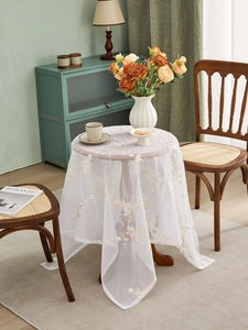 Detail of white lace tablecloth with yellow floral embroidery and delicate mesh texture