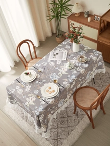 Detail of grey floral tablecloth with white lace edges on a modern dining table set