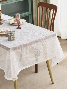 Detail der weißen Spitzentischdecke mit feinem rosa Pflaumenblüten-Stickmuster