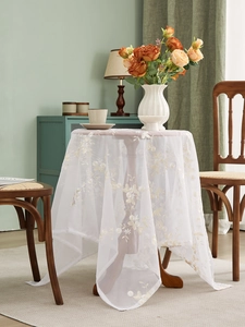 Detail of delicate yellow floral embroidery on a white translucent lace tablecloth