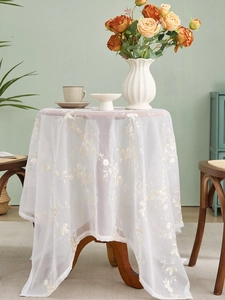 Close-up of white lace tablecloth with yellow floral embroidery on a wooden table