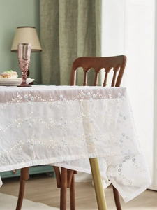 Detail der Stickerei mit blauen und goldenen Blumen auf weißer transparenter Tischdecke