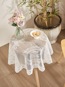 Close-up of white lace tablecloth with floral patterns and delicate scalloped edges