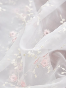 Detailaufnahme von weißem Tüllstoff mit feinem rosa Blumen-Stickmuster und Textur