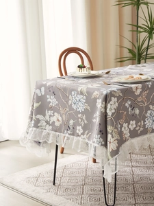 Detailed view of rectangle tablecloth with floral patterns and white lace trim edge