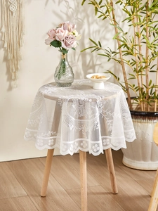 Close-up of white lace tablecloth featuring delicate hollow flower patterns and wavy edges