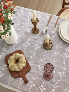 Detail einer lila Spitze-Tischdecke mit floralen Stickereien und Rankenmustern