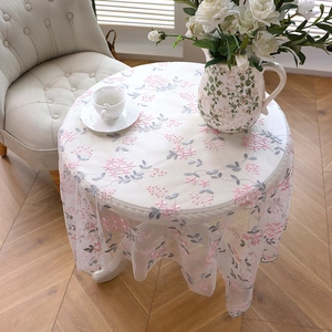 Detail of round mesh tablecloth featuring pink floral embroidery and elegant lace edges