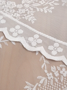 Close-up of intricate floral embroidery and scalloped edges on white lace tablecloth