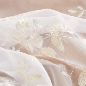 Elegant white lace tablecloth featuring delicate yellow floral embroidery on sheer fabric