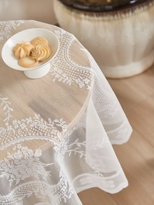 Detail of white lace tablecloth with intricate floral patterns and scalloped edges