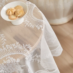 Elegant white lace round tablecloth with vintage floral embroidery on wooden table