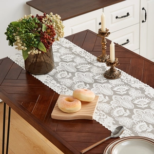Elegant white lace table runner with floral embroidery on dark wood table for home decor