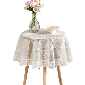 White round lace tablecloth with floral embroidery and wavy hollow edges on wood table