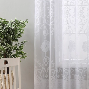 White damascus lace sheer curtain with embroidered hem hanging in a sunlit living room