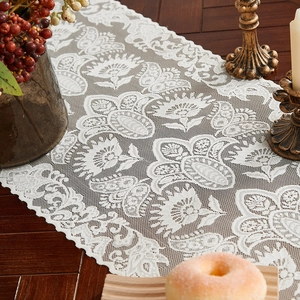 Elegant white lace table runner with floral patterns and scalloped edges on dark wood