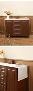 Detail of dark wood sideboard featuring four drawers and a white jacquard table runner