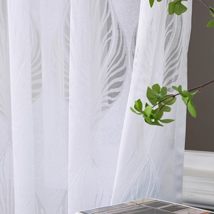 Close-up of white semi-transparent lace curtain with leaf pattern and greenery