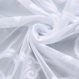 Close-up of white lace sheer curtain fabric with delicate floral pattern and soft folds