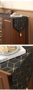 Detail of black table runner with golden geometric patterns and white fringe tassels