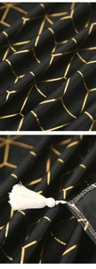 Detail of black satin table runner with golden hexagonal pattern and white cotton tassels