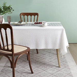 Close-up of white rectangular cotton linen tablecloth with wave texture and tassel fringe